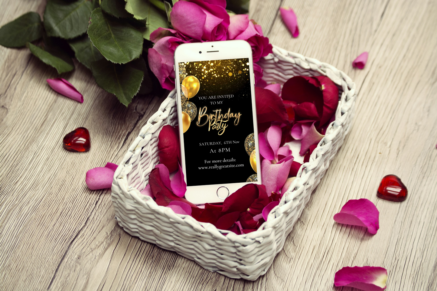 Phone with birthday party invitation on screen in a basket of flowers