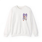 An off-white crewneck sweatshirt featuring a graphic print of a purple patterned bow and a hanging white veil decorated with small orange flowers and black details, shown against a plain white background.