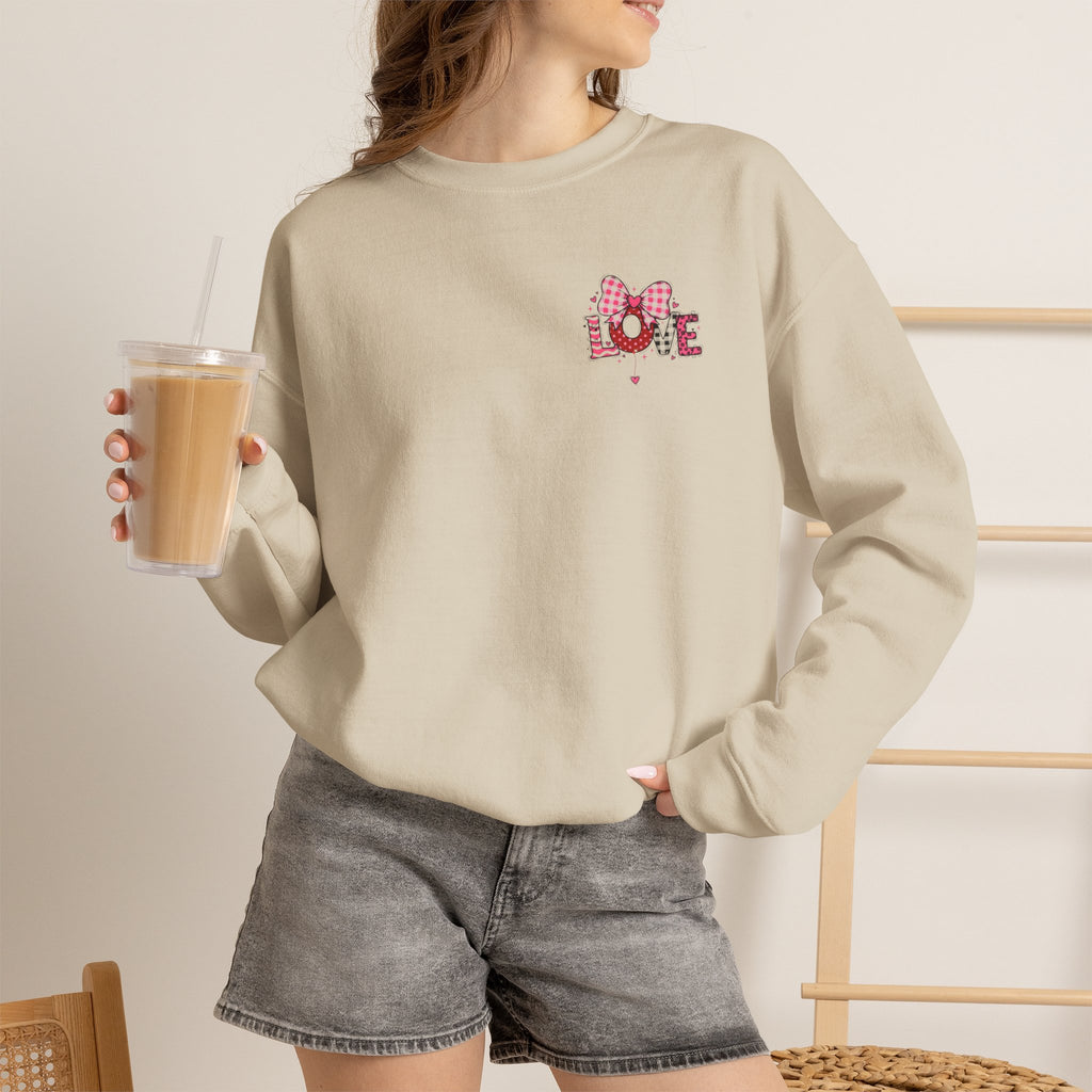 Person wearing a beige sweatshirt with a pink flower design, holding a drink.