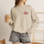 Person wearing a beige sweatshirt with a pink flower design, holding a drink.