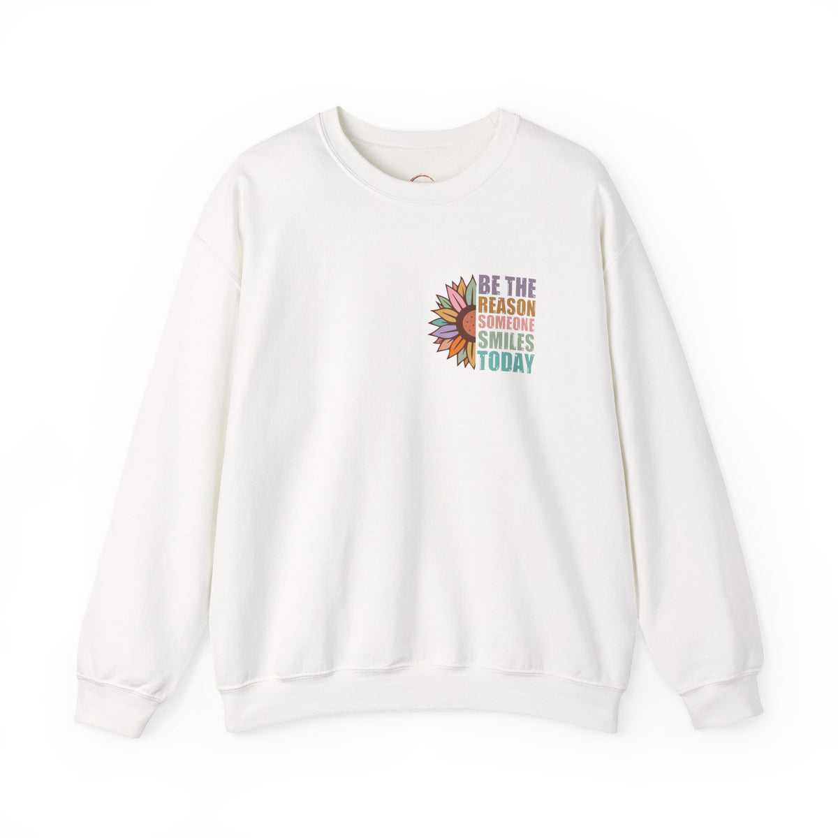 An off-white crewneck sweatshirt featuring a colorful graphic on the left chest with a sunflower and the text 'BE THE REASON SOMEONE SMILES TODAY'.