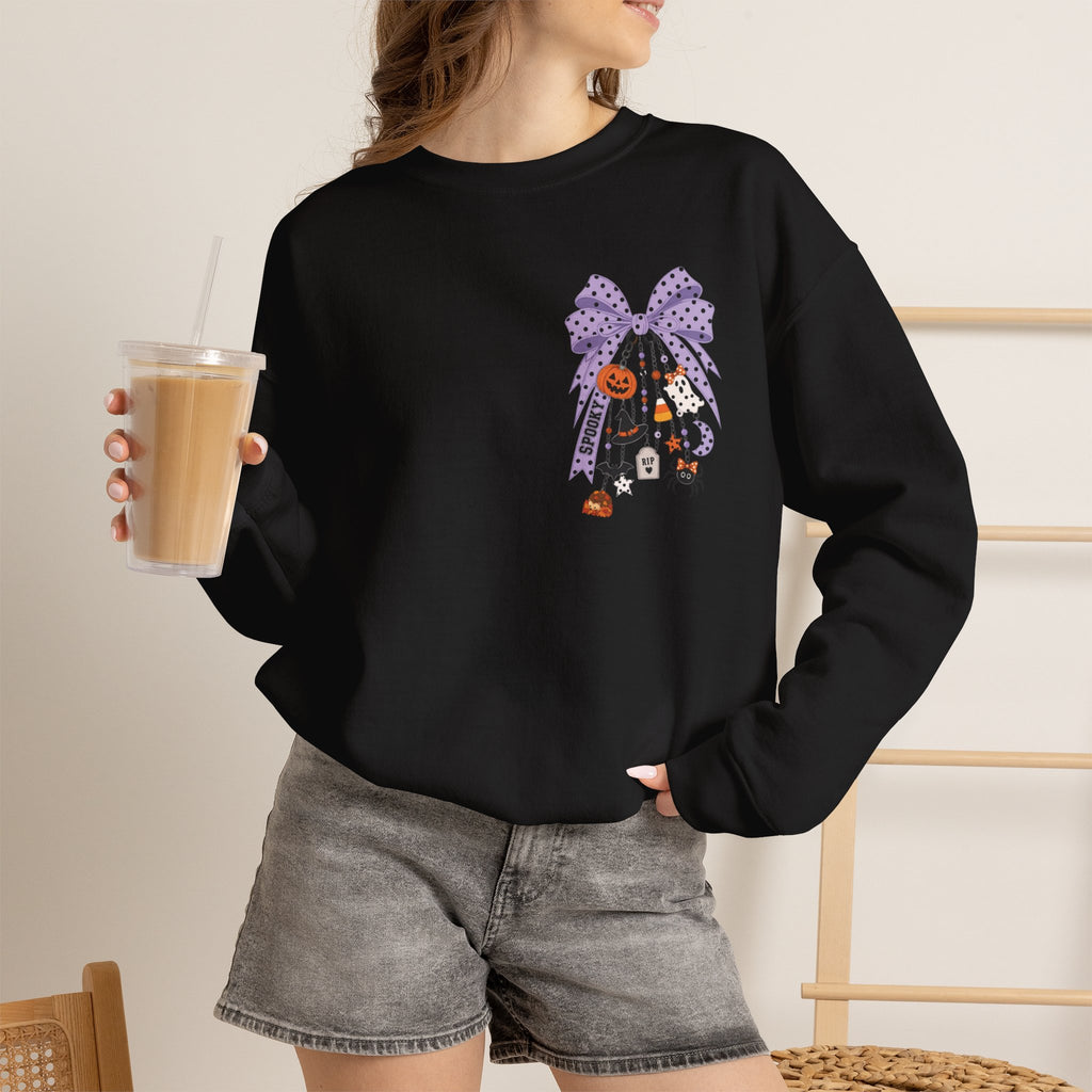A woman wearing a black crewneck sweatshirt with a colorful anatomical heart graphic and the words 'Registered Nurse' on the front, paired with gray denim shorts and holding an iced coffee.