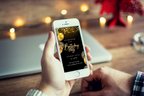 Hand holding a smartphone with a birthday party invitation on a blurred background of a cozy room.